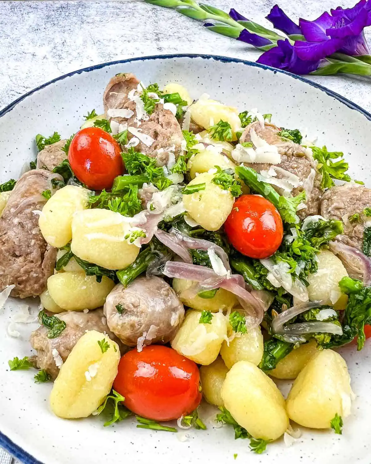 Gnocchi with sausage and tomatoes on a plate.