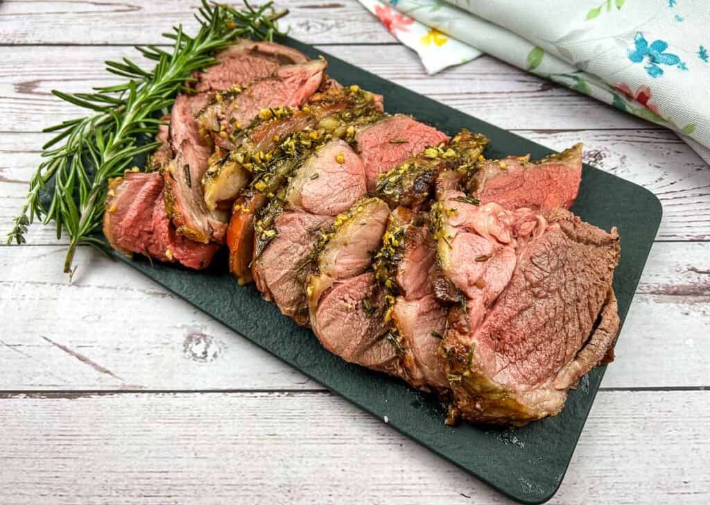 Smoked lamb with rosemary and thyme on a wooden board.