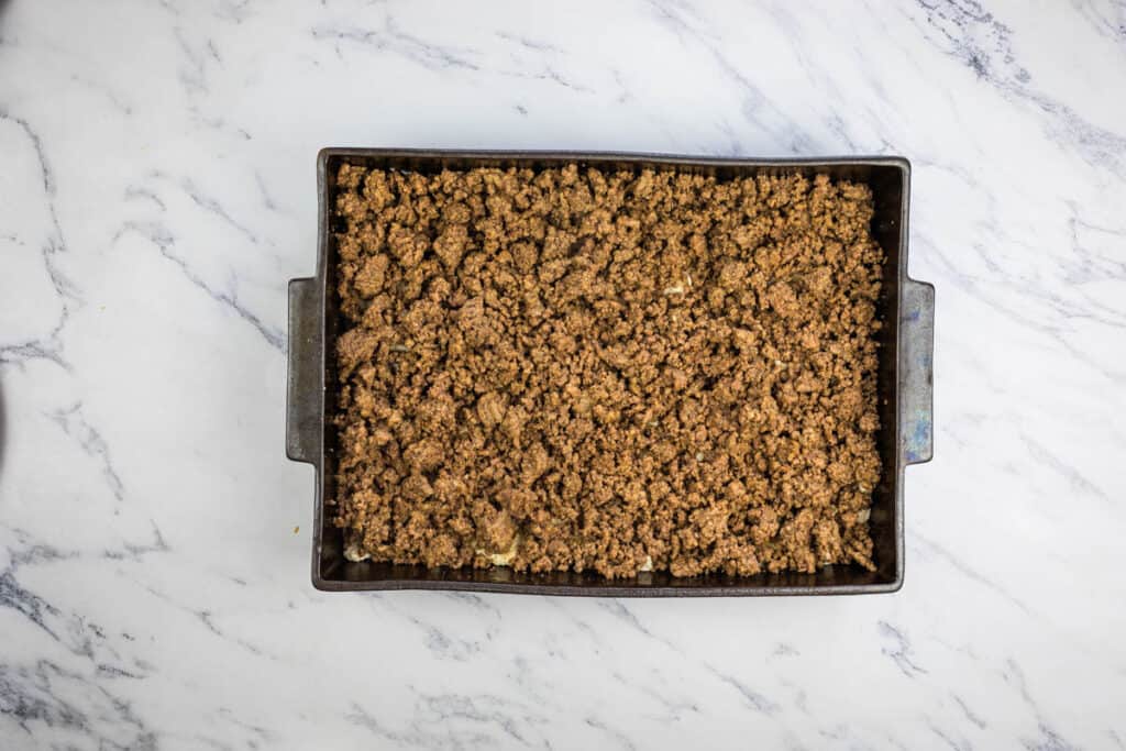 A square pan filled with a brown crumble.