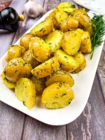 Ukrainian potatoes with dill on a white plate.