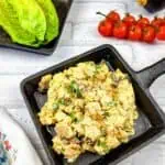 A skillet with eggs, tomatoes and lettuce on a white background.