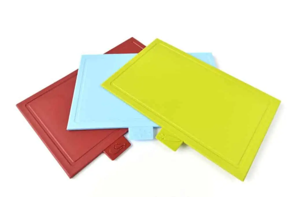 Three colorful plastic cutting boards on a white surface.