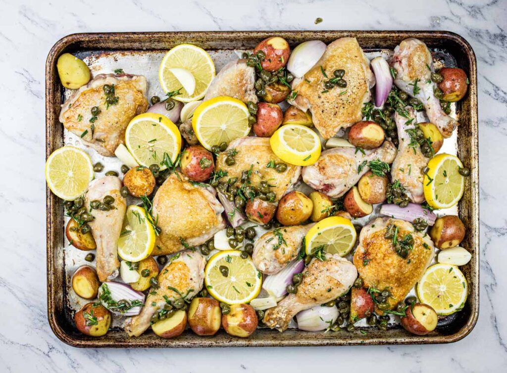 Roasted chicken with lemon and potatoes on a baking sheet.