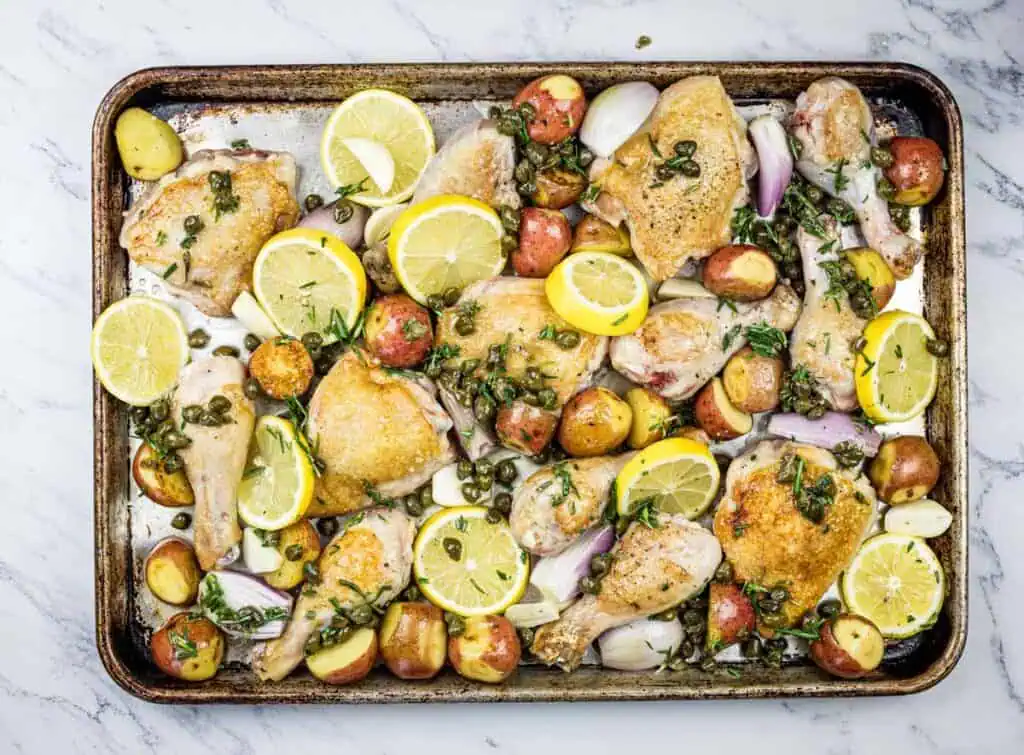 Roasted chicken with lemon and potatoes on a baking sheet.