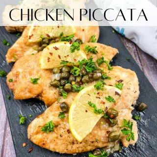 Chicken piccata on a black slate plate.