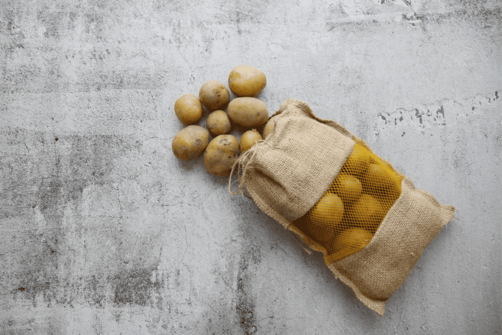 Potatoes in a sack on a concrete surface.