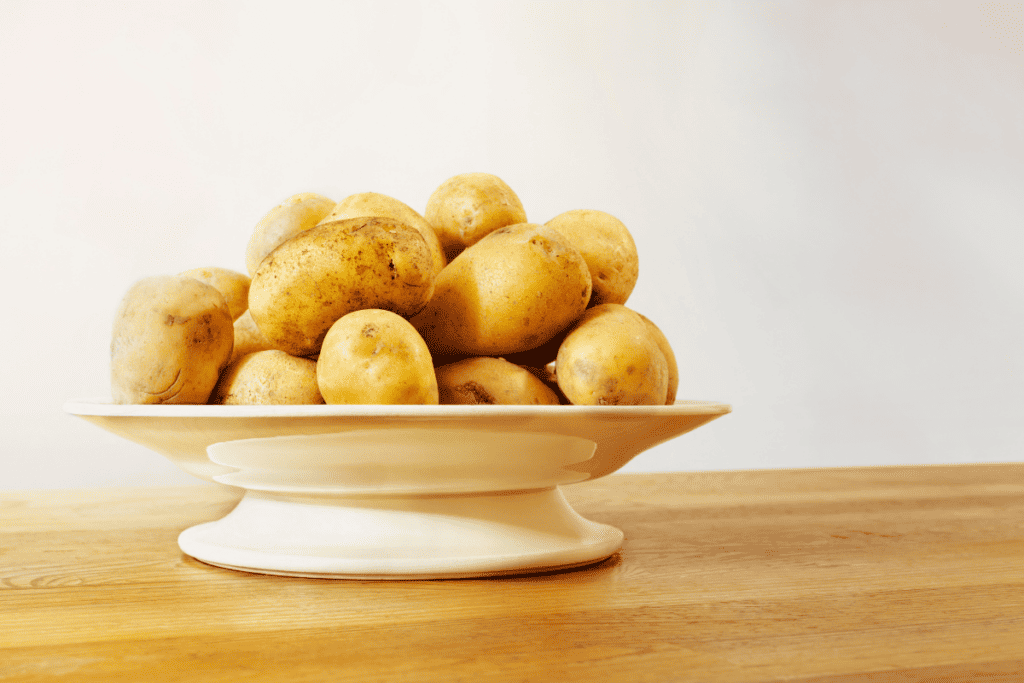 Potatoes in a bowl on a wooden table.