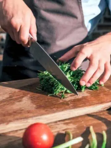 A man is slicing vegetables on a cutting board.