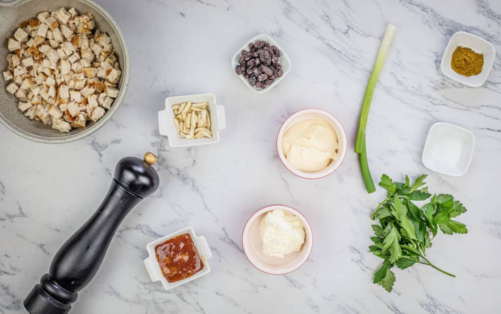 The ingredients for coronation chicken salad on a marble table.