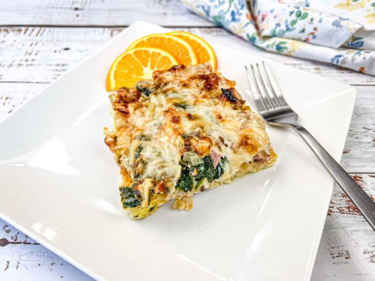 A slice of breakfast casserole on a white plate with orange slices.