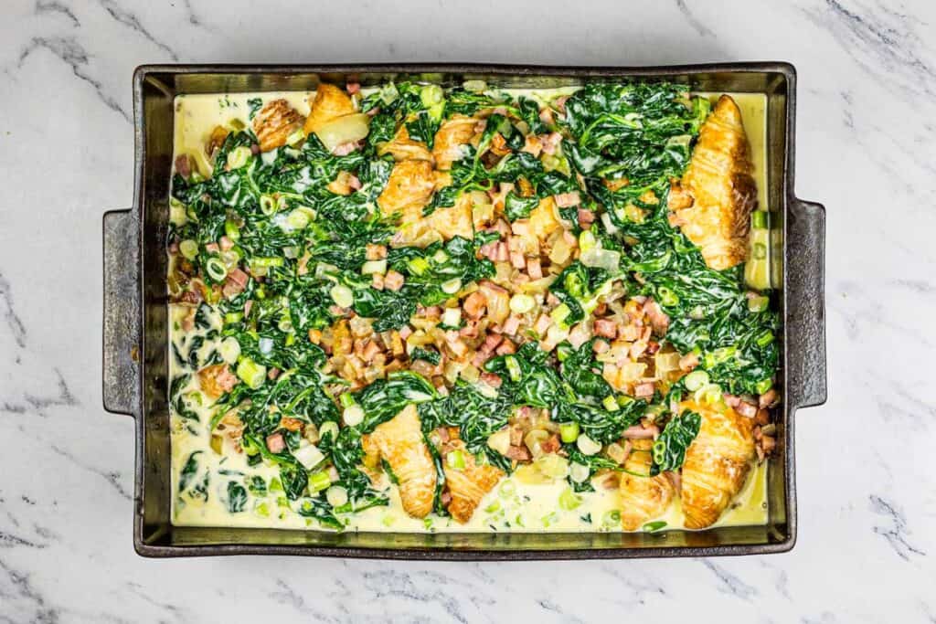 A baking dish with spinach and egg in it.