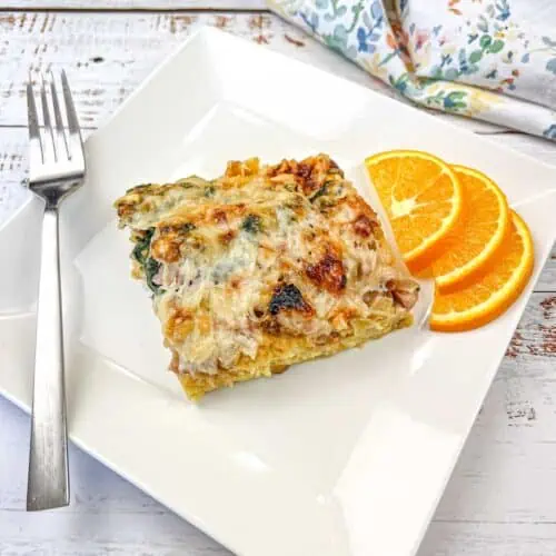 A slice of breakfast casserole on a white plate with orange slices.