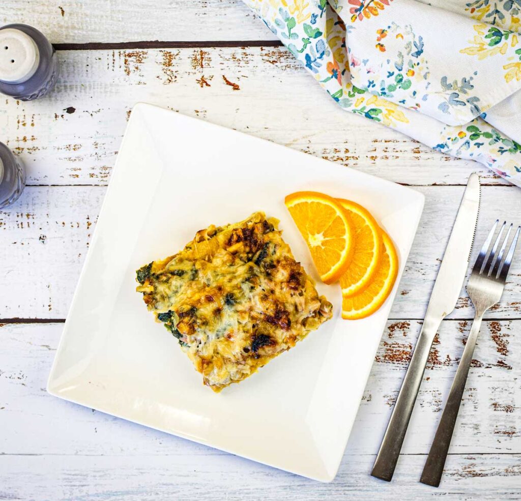 A plate of Croissant Breakfast Casserole with a slice of orange on it.