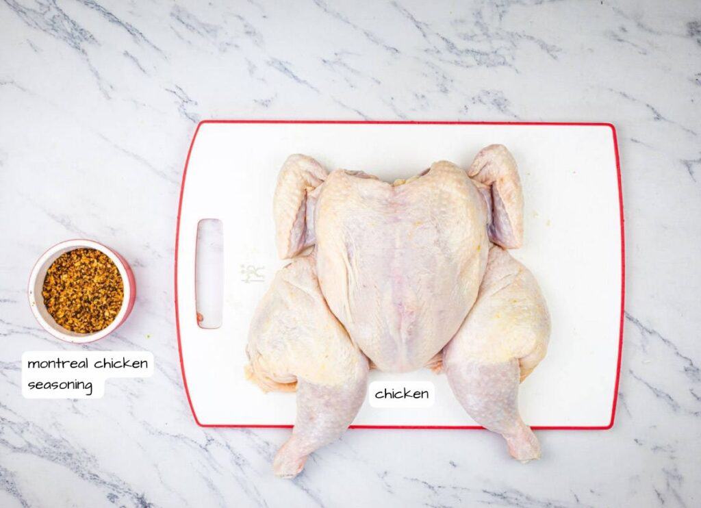 A raw chicken alongside montreal chicken seasoning on a white countertop.