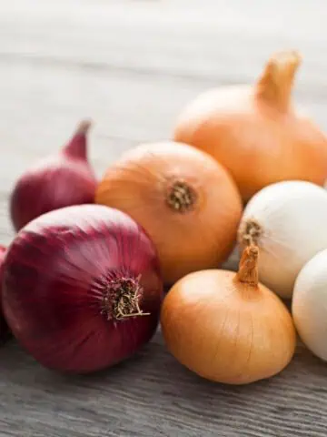 Assorted onions on a wooden surface.