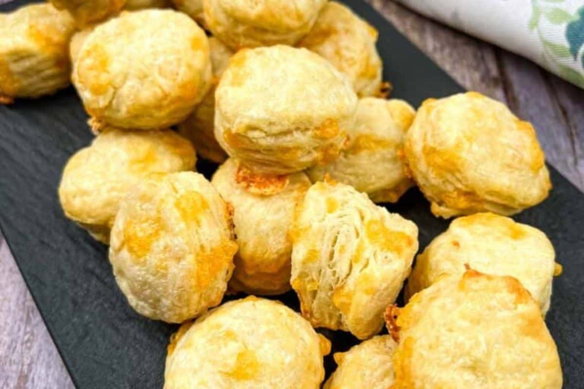 A plate of mini flaky cheese biscuits and a cup of coffee.