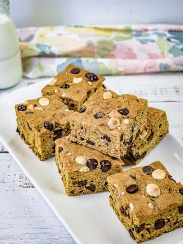 Pieces of pumpkin blondies on a white rectangular plate.