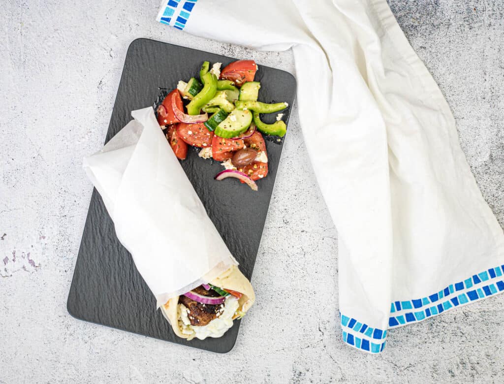 Top-down shot of Greek Meatball Pita Sandwich on a black slate plate.