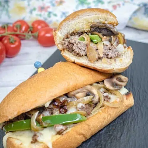 Halves of Ground Beef Philly Cheesesteak on a slate plate.