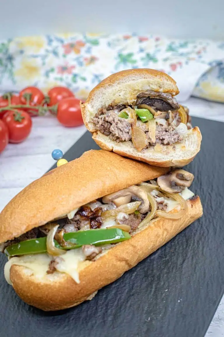 Halves of Ground Beef Philly Cheesesteak on a slate plate.