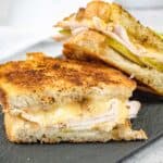 Two halves of a Turkey & Apple Grilled Cheese on a slate plate.