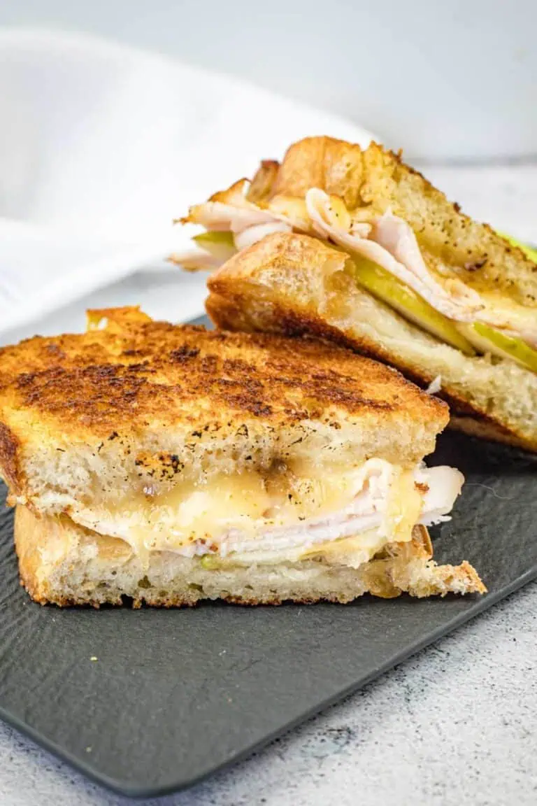 Two halves of a Turkey & Apple Grilled Cheese on a slate plate.