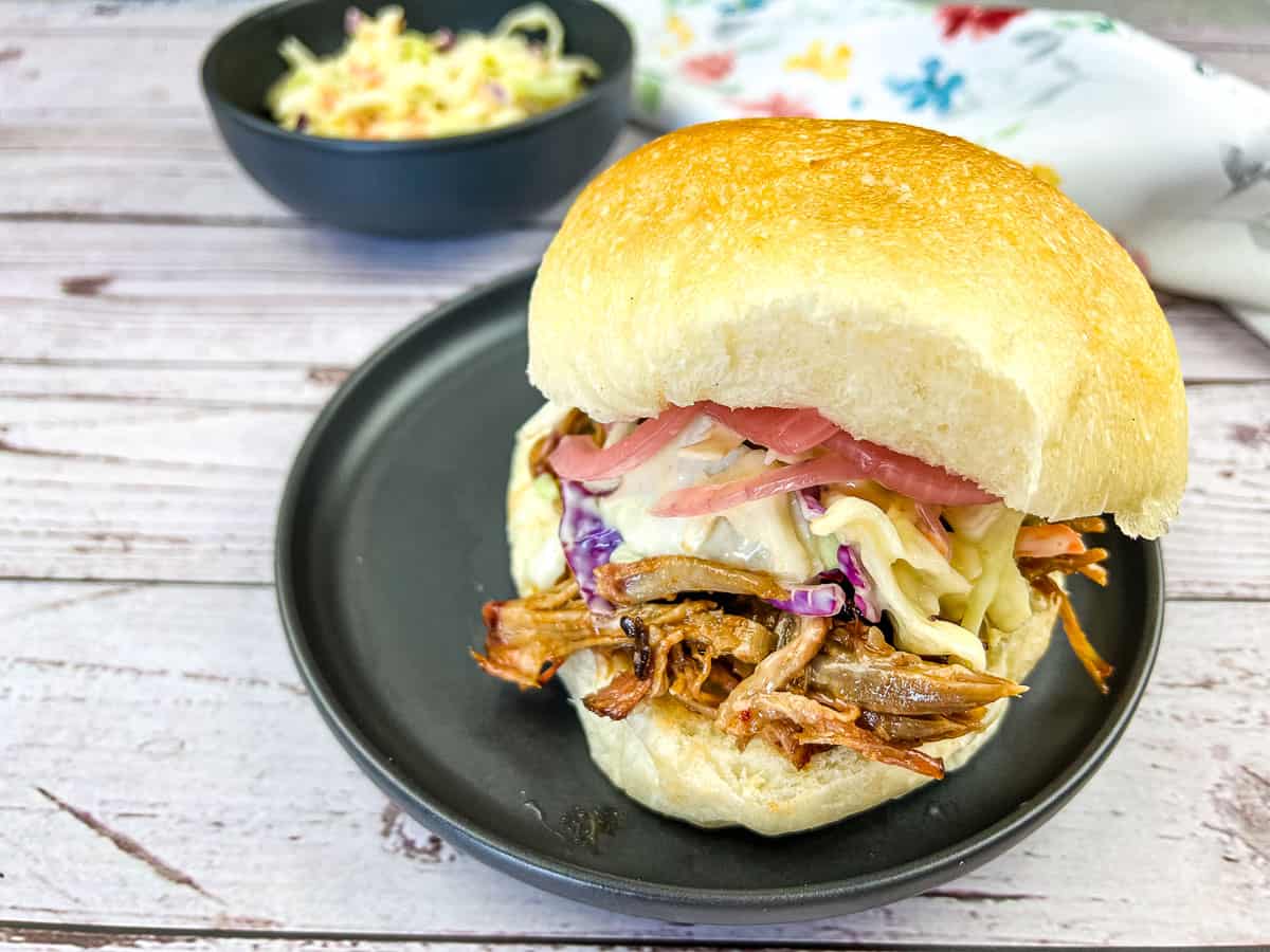 Pulled Pork Sandwich with Coleslaw on a black plate.