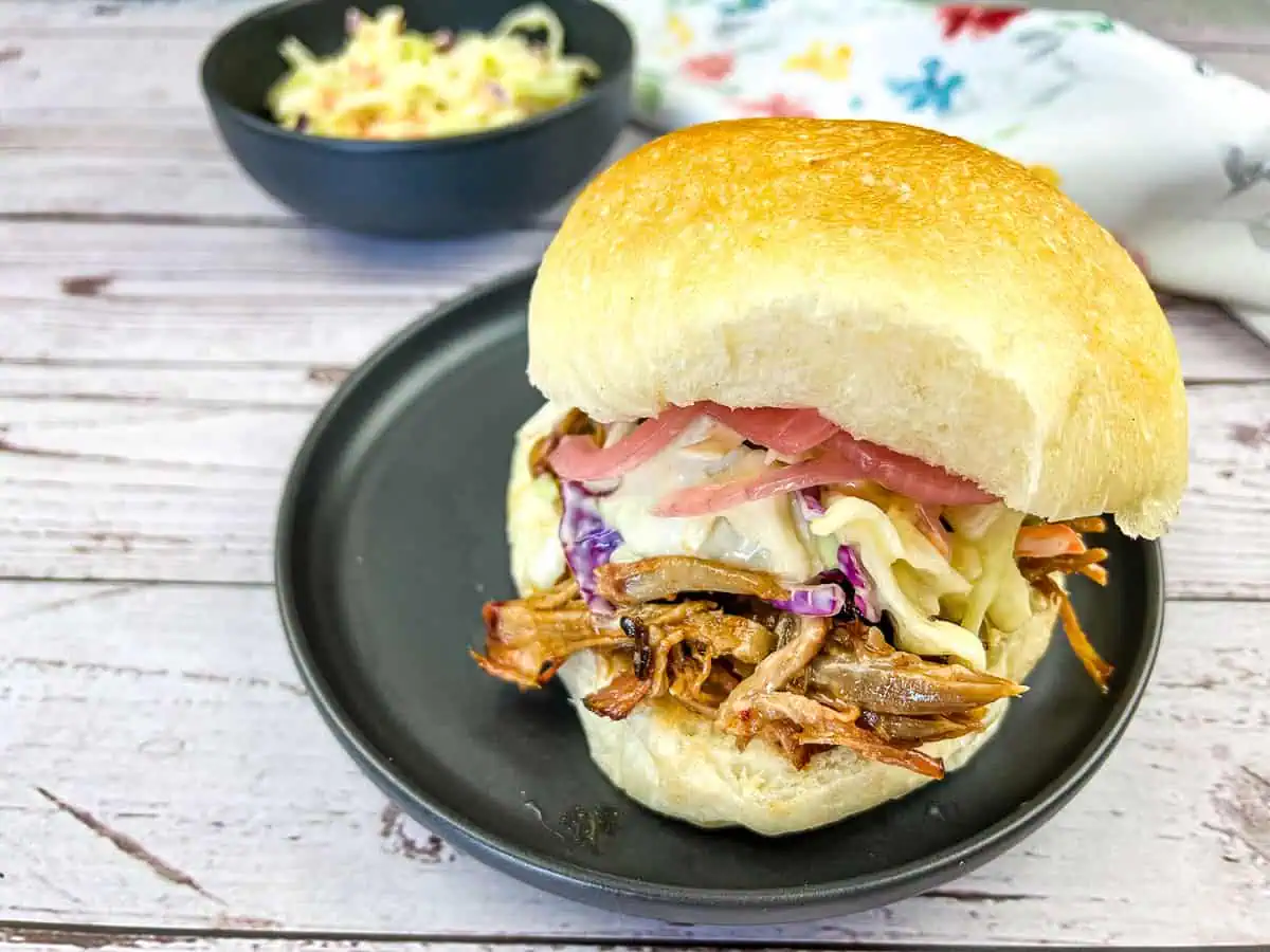 Pulled Pork Sandwich with Coleslaw on a black plate.