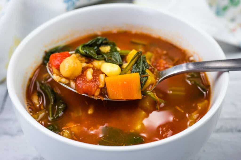 Copycat Panera Bread&rsquo;s 10 Vegetable Soup with a spoon lifting it.