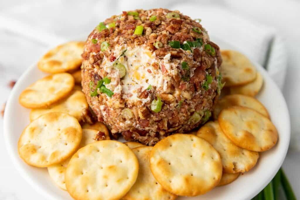A Pecan Bacon Cheeseball with crackers around.