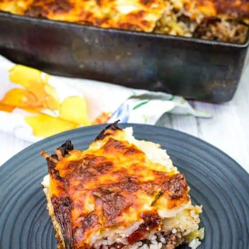 A black plate with a Cabbage Roll Casserole near a casserole dish.