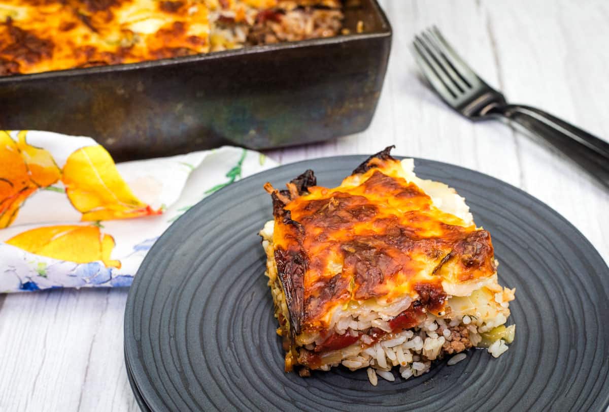 A slice of layered cabbage roll casserole served on a dark plate.