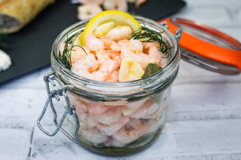Pickled Shrimp with a sliced lemon and dill in a jar.