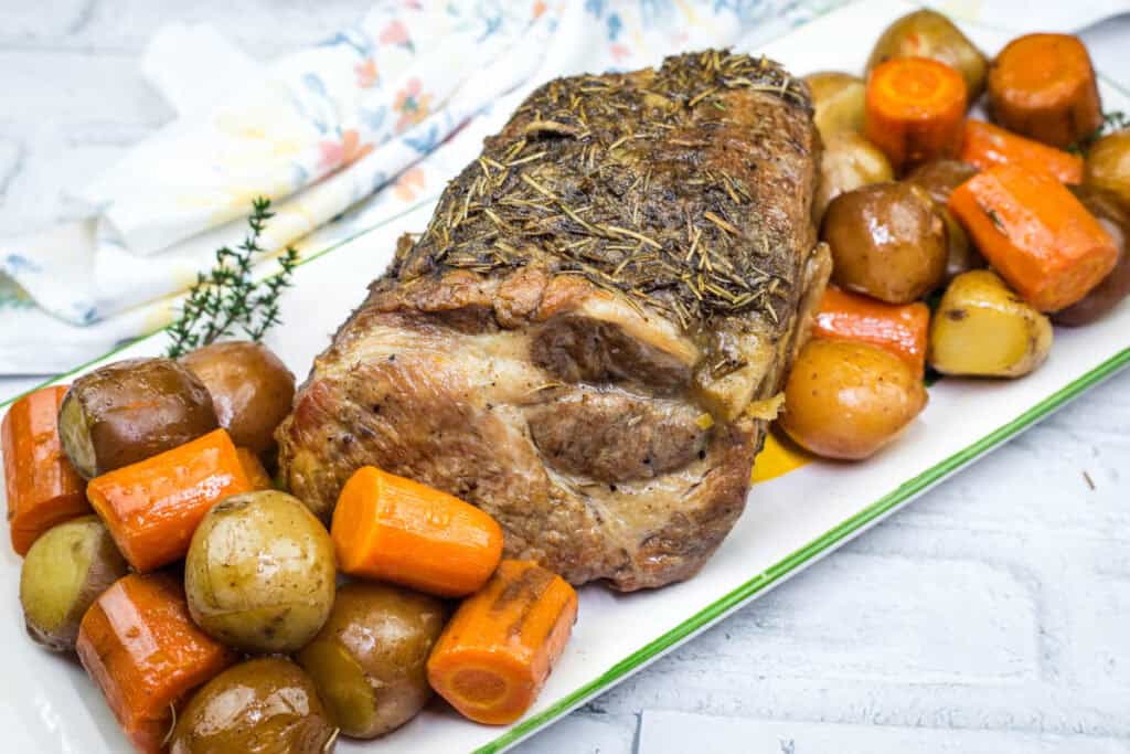 A plate of Slow Cooker Herb-Crusted Pork Roast with vegetables beside.