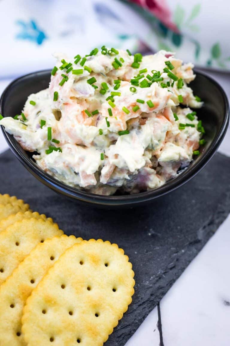 A black bowl with Smoked Salmon Tartine and biscuits on a plate.