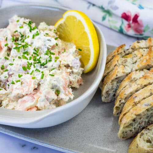 A bowl of Smoked Salmon Tartine with a lemon slice and toasted baguette.