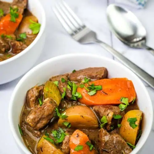 A bowl of Classic beef stew beside the spoon and fork.