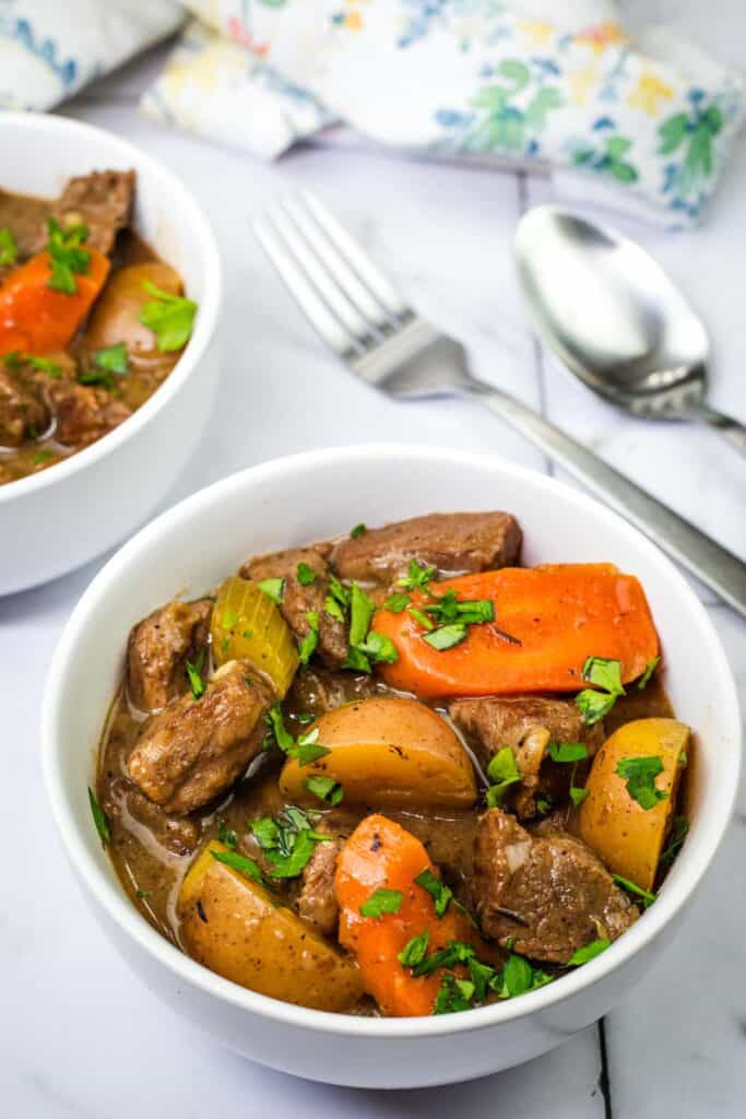 A bowl of Classic beef stew beside the spoon and fork.