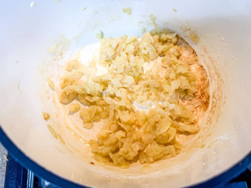 Adding the minced garlic in a white pot.
