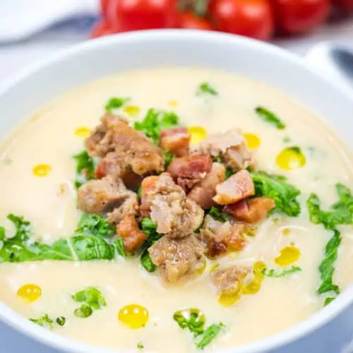 A white bowl of Creamy Tuscan Soup With Sausage & Kale.