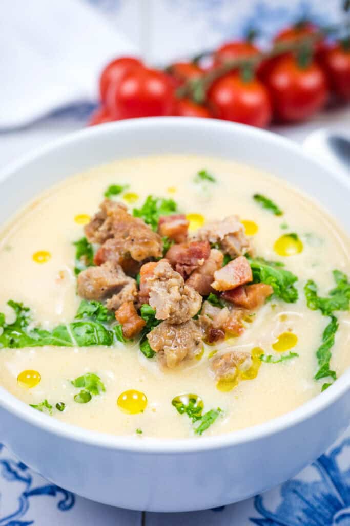 A white bowl of Creamy Tuscan Soup With Sausage & Kale.