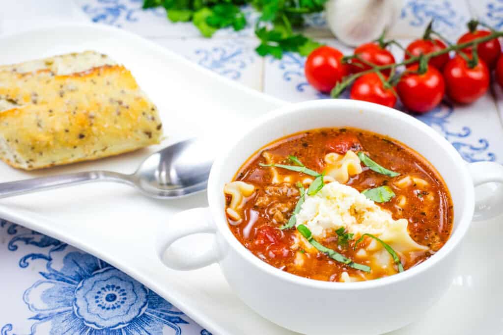 A white bowl filled with Lasagna soup topped with chopped fresh basil.
