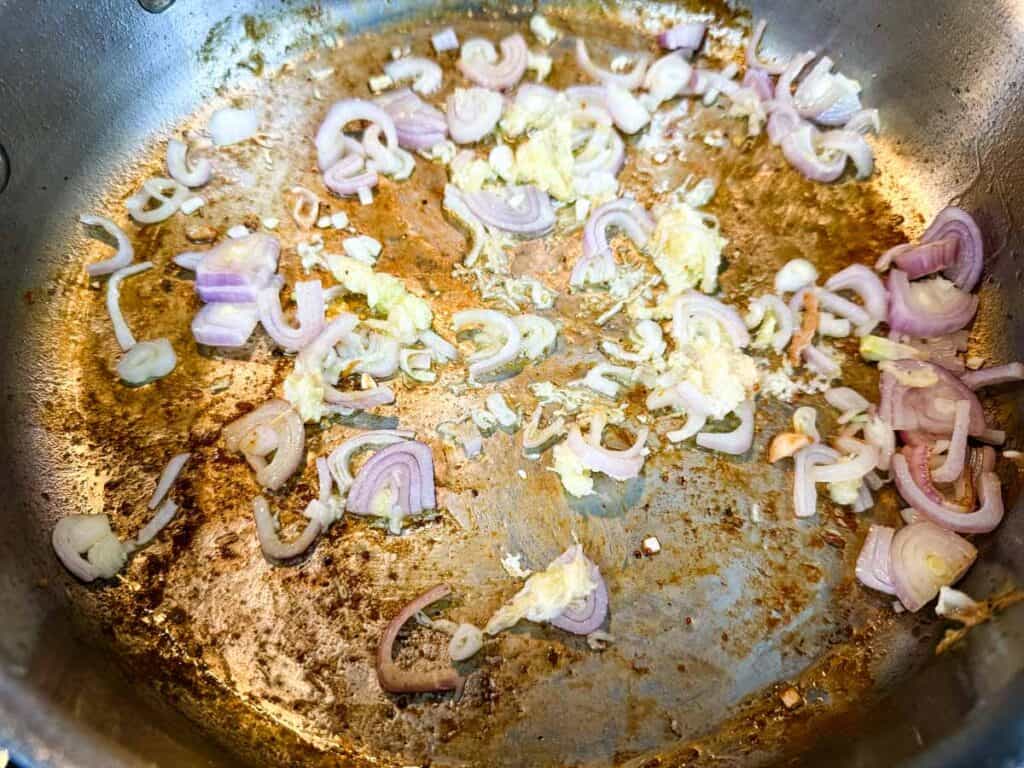 Sliced shallots and minced garlic saut&eacute;ing in a pan.