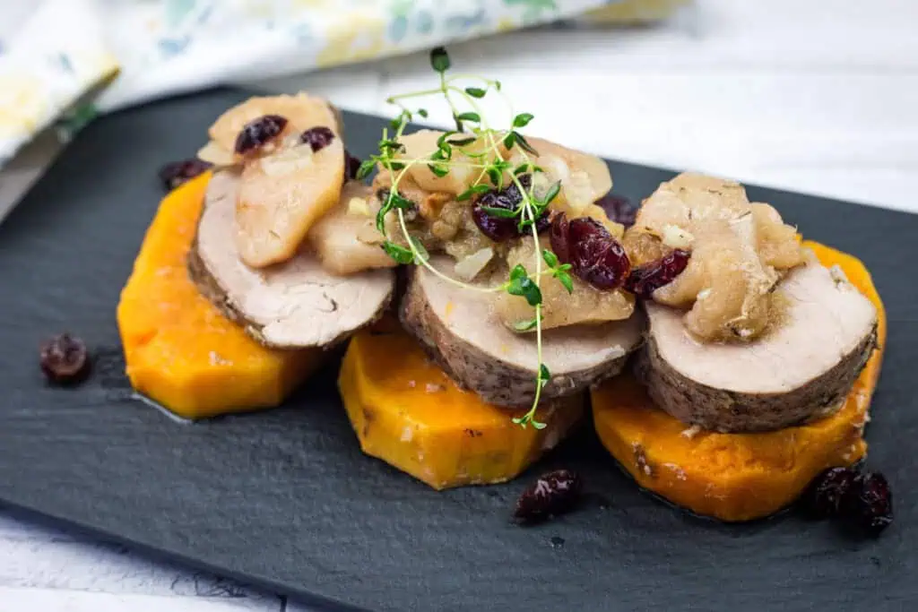 A serving of Slow Cooker Pork Tenderloin with Sweet Potatoes & Apples on a black platter.