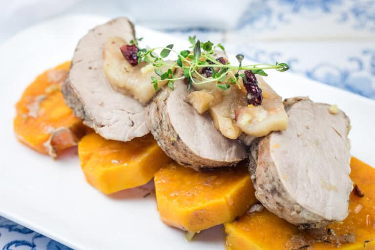 A serving of Slow Cooker Pork Tenderloin with Sweet Potatoes & Apples on a white platter.
