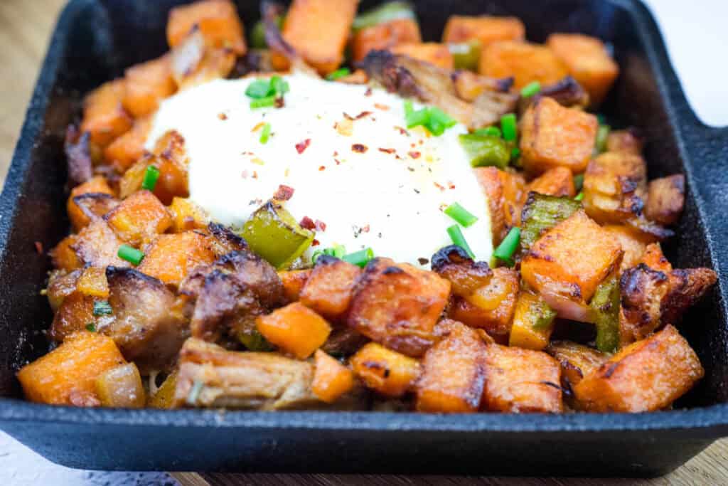 A delicious serving of Sweet Potato Hash with Pulled Pork in a black skillet.