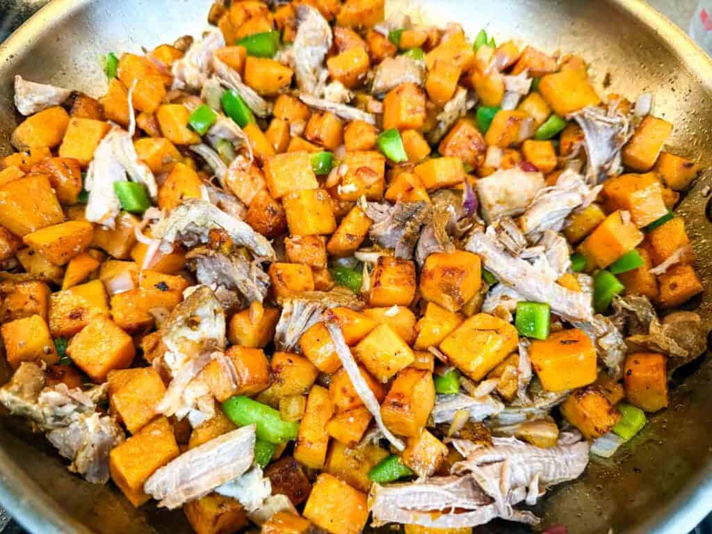 Butter, chopped onion, minced garlic, green bell pepper and pulled pork in a pot.