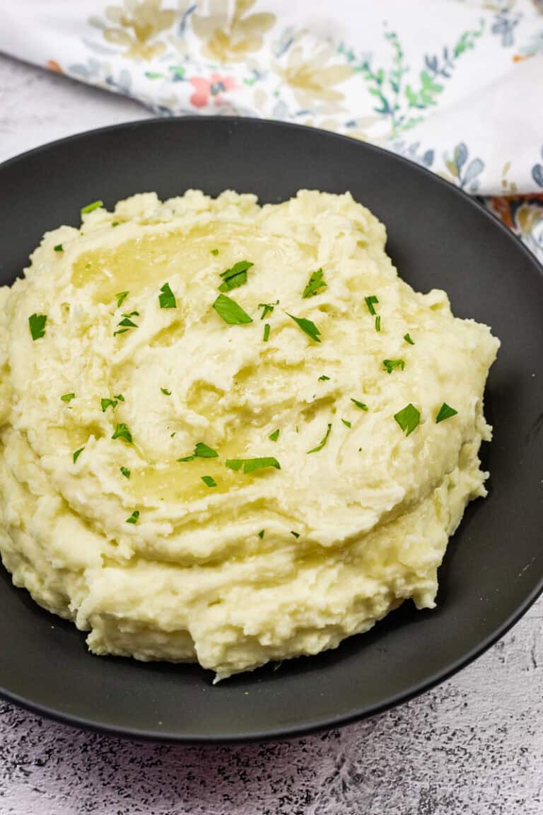Mashed potatoes with cream cheese topped with melted butter and garnished with fresh parsley.