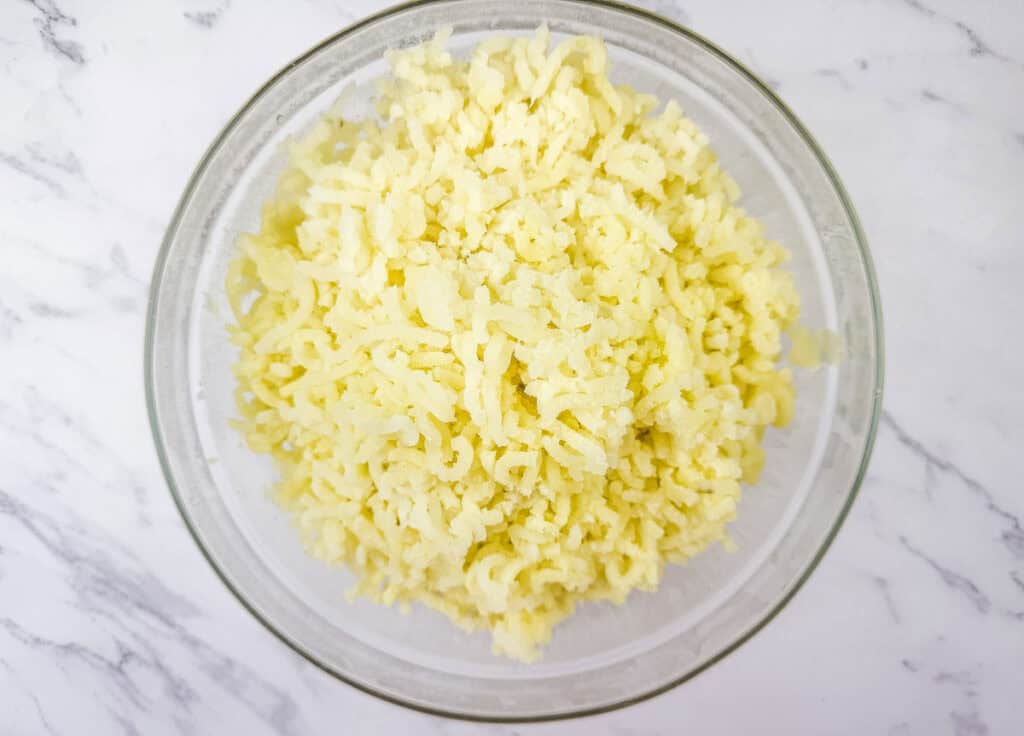Glass bowl filled with freshly riced potatoes, creating a light and fluffy texture.
