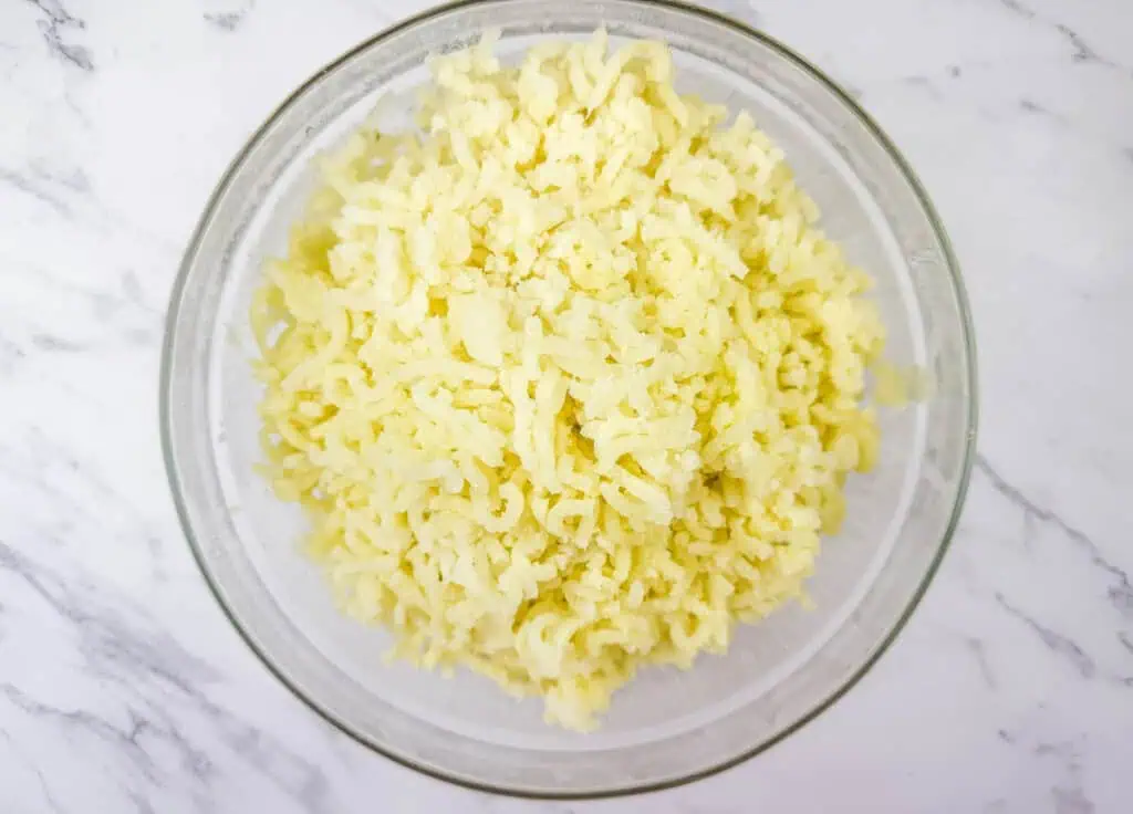 Glass bowl filled with freshly riced potatoes, creating a light and fluffy texture.